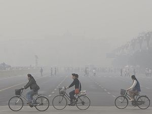 Cyklisté na náměstí Tiananmen v Pekingu pod hustým závojem smogu. (AP/SITA)