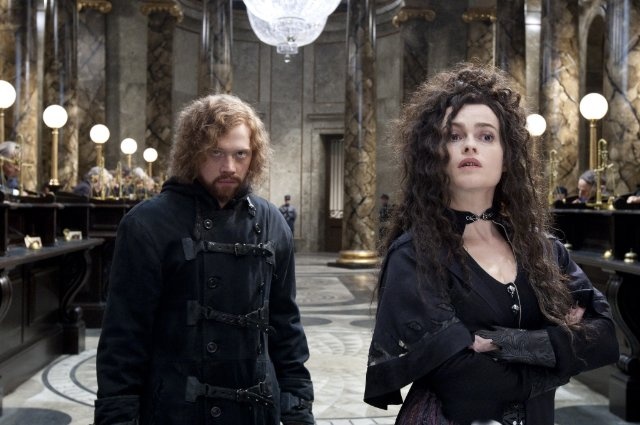 Film je odlehčen řadou humorných situací: Ron coby Dragomir Despard a Hermiona jako Belatrix Lestrangeová (© 2011 WARNER BROS. ENTERTAINMENT INC.)